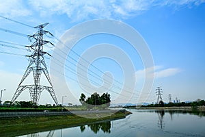 A High voltage post, and electrical transmission tower with high voltage lines under the blue sky background.