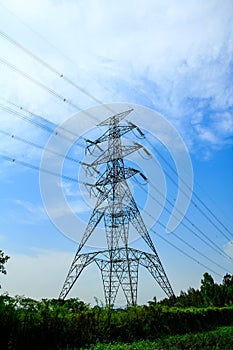 A High voltage post, and electrical transmission tower with high voltage lines under the blue sky background.