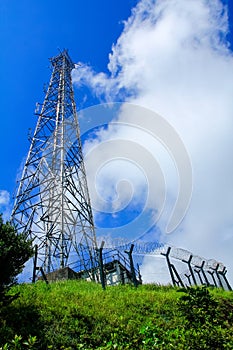 A High voltage post, and electrical transmission tower with high voltage lines under the blue sky background.