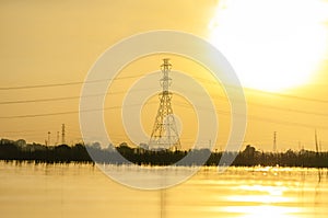 High voltage post on landscape view at morning with Sky yellow and river background