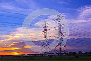 High voltage post tower and power line on sunset sky background