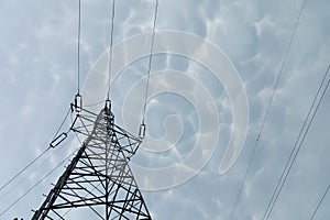 A steel power transmission pole against a backdrop of storm clouds.