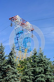 High voltage power line. Great height above the trees. Spring sky.