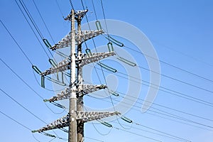 High-voltage power line grey metal prop with many wires vertical view over clear cloudless blue sky