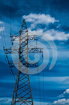 High voltage power line tower with a blue sky on backgound