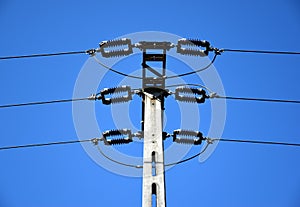 High voltage power lines and concrete electrical pole in low angle abstract view.