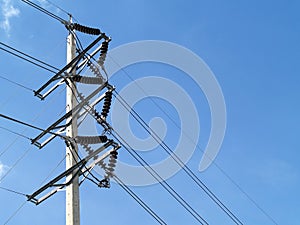 high voltage power lines connected to brown ceramic electrical insulators on steel beam on concrete electric high voltage pole