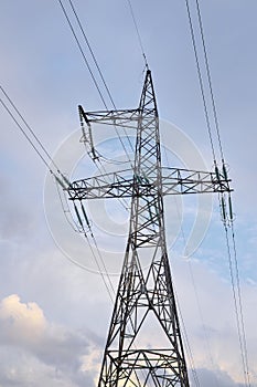 High voltage power lines with electricity pylons against the blue sky.