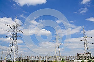 High voltage power lines with electricity pylons at blue sky.