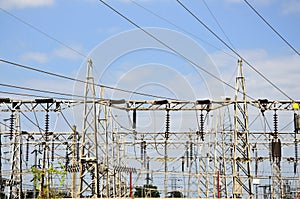 High voltage power lines with electricity pylons at blue sky.