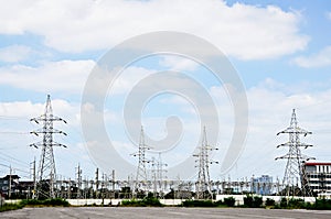 High voltage power lines with electricity pylons at blue sky.