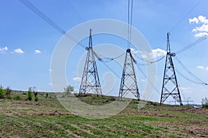 High-voltage power lines in green field against blue sky