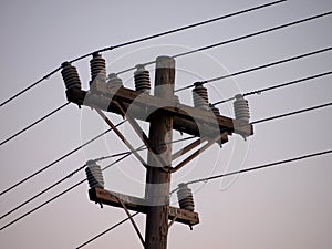 High Voltage Power Lines lines on wooden Utility pole at dusk