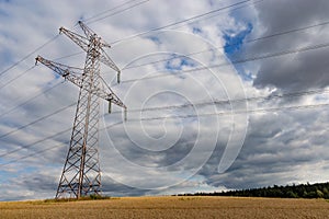 High voltage power lines and power pylons in a agricultural landscape on a sunny day with cirrus clouds in the blue sky