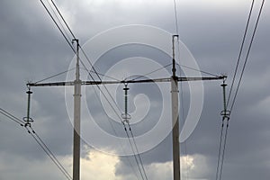 High-voltage power lines and a transformer with wires against the grey cloudy sky