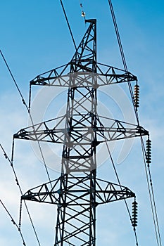 A high voltage power pylons against blue sky and sun rays