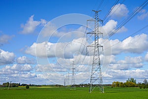 High-voltage power transmission line in a cereal field on a background of blue sky
