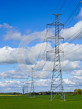 High-voltage power transmission line in a cereal field on a background of blue sky