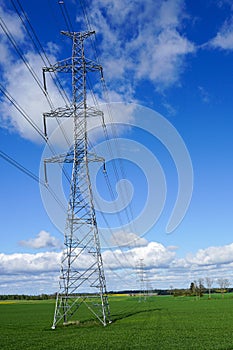 High-voltage power transmission line in a cereal field on a background of blue sky