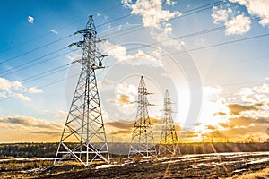 High-voltage power transmission towers in sunset sky background