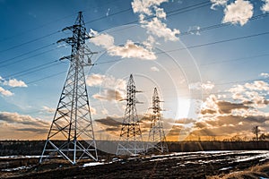 High-voltage power transmission towers in sunset sky background