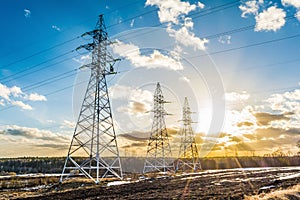 High-voltage power transmission towers in sunset sky background