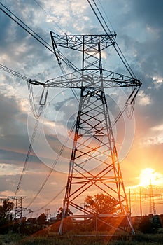 High-voltage power transmission towers in sunset sky background.