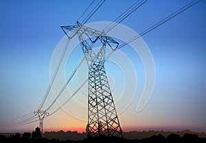 High Voltage Pylon with Electric Wires with Landscape Silhouette and Sunrise