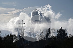 High-voltage pylon with industrial chimneys in the background