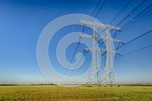 High voltage pylons against a blue sky in dramatized colors