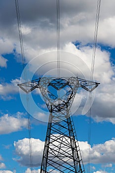 High voltage pylons against a blue sky with white clouds.
