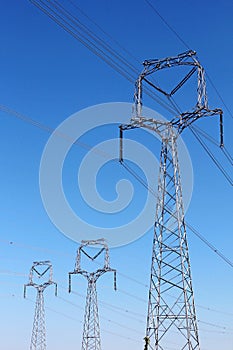 high voltage pylons under blue sky