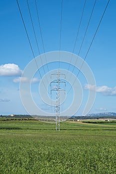 High voltage tower and cable line in the countryside under a blue sky