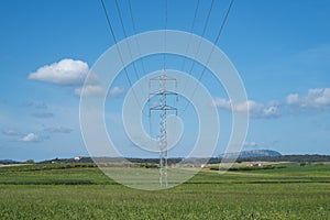 High voltage tower and cable line in the countryside under a blue sky