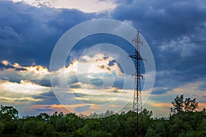High-voltage tower dark dramatic clouds sun`s rays