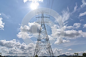 High voltage tower, Electric post and electric cable on the field in the countryside with white cloudy and blue sky background.