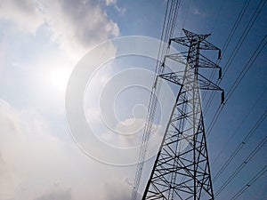 High voltage tower or electricity transmission power lines in the cloudy blue sky