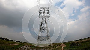 High voltage tower on green grass strewn across green grass