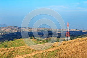 High-voltage tower on mountain with meadow,electrical poles and cables in rural areas