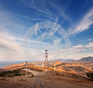 High voltage tower in mountains at sunset. Electricity pylon system