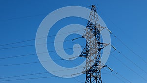 High-voltage tower with power line wires on background clear blue sky