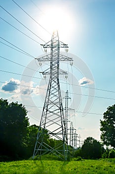 High voltage tower with power wires against the background of the sun and clouds. The concept of a source of electricity. Energy