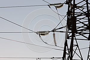 High-voltage towers against the blue sky. High-voltage electrical insulator. Electric hub on pole. Wires of high voltage in sky.