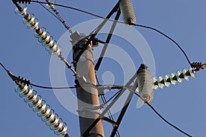 High-voltage towers against the blue sky. High-voltage electrical insulator. Electric hub on pole. Wires of high voltage in sky.