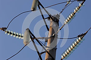 High-voltage towers against the blue sky. High-voltage electrical insulator. Electric hub on pole. Wires of high voltage in sky.