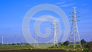 High voltage towers with cable lines in countryside with blue sky