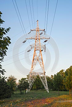 High voltage towers with electrical wires on dark cloudy sky background. Electricity transmission lines, electric power station