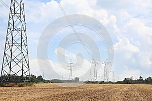 High voltage towers with electricity transmission power lines in field on sunny day