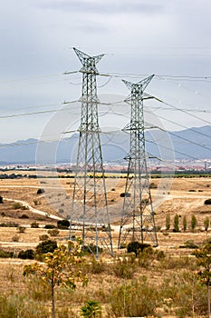 High voltage towers over dry field and city in the background