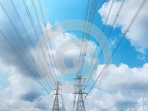 High Voltage Towers and Power Lines Against Blue Cloudy Sky